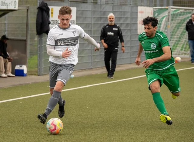 Two football players contesting the ball on a football pitch.